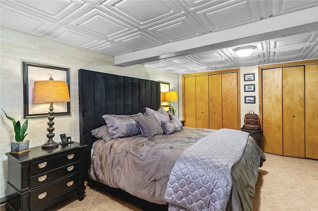 bedroom featuring light tile patterned floors, an ornate ceiling, and multiple closets