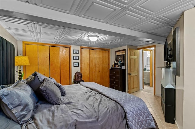 bedroom with light tile patterned floors, an ornate ceiling, and two closets