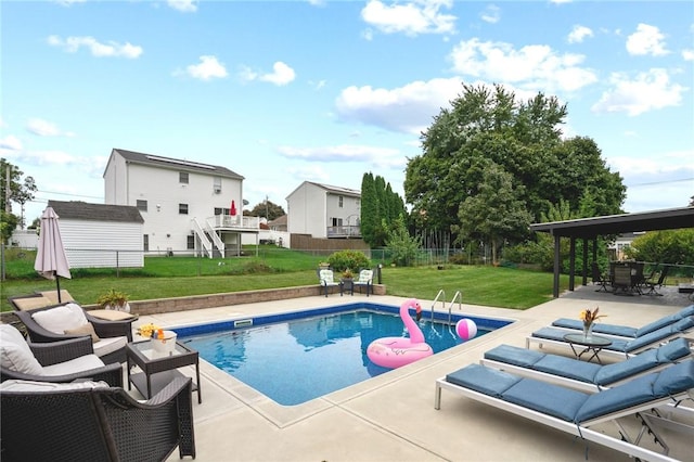 outdoor pool featuring a fenced backyard, a yard, a patio area, a storage unit, and an outbuilding