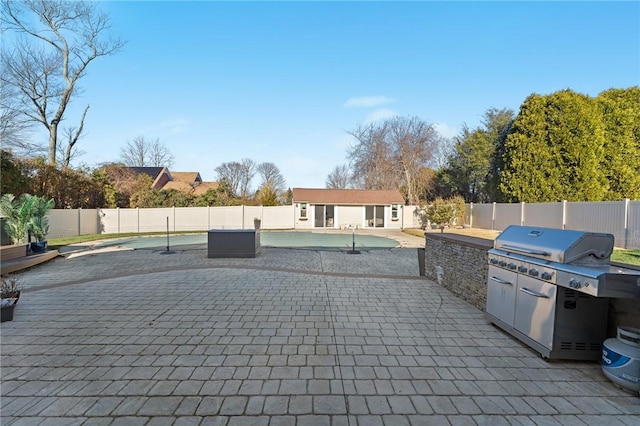 view of patio featuring an outbuilding, a fenced in pool, exterior kitchen, a fenced backyard, and a storage structure