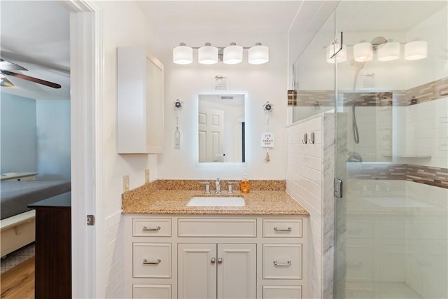 full bathroom with a stall shower, vanity, and ceiling fan