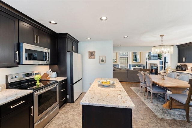 kitchen with open floor plan, appliances with stainless steel finishes, a kitchen island, and dark cabinets