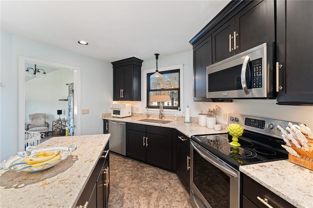 kitchen featuring a sink, light stone countertops, dark cabinets, and stainless steel appliances