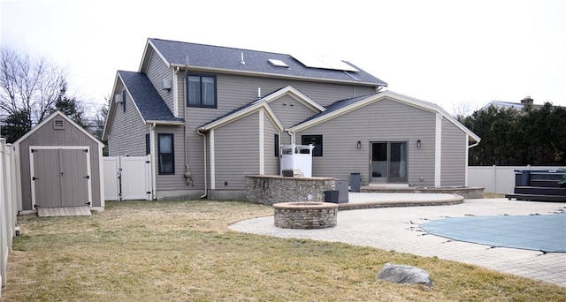 rear view of property with a gate, a patio, a fenced backyard, a fire pit, and a storage shed