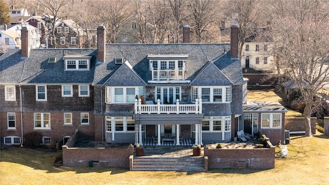 back of house featuring a balcony, a lawn, and a chimney