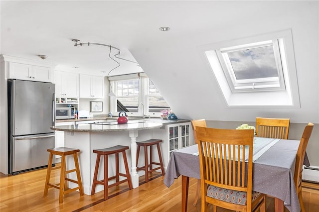 dining room with a skylight and light wood-type flooring