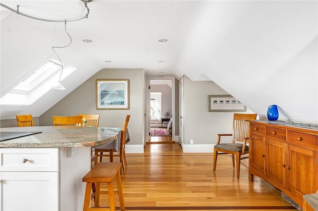 additional living space with baseboards, recessed lighting, light wood-style floors, and lofted ceiling with skylight