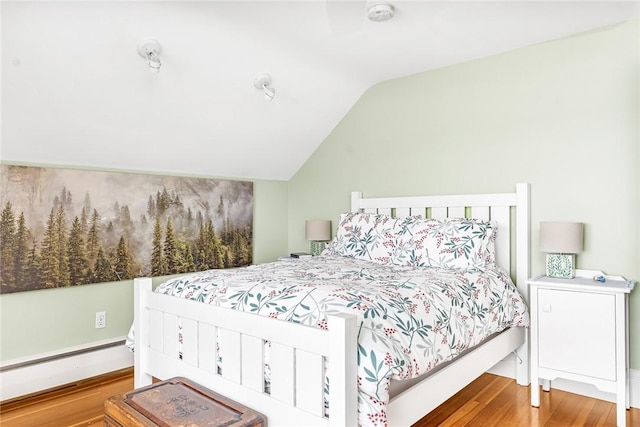 bedroom with wood finished floors, lofted ceiling, and baseboard heating