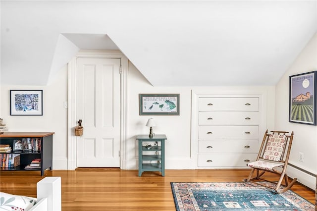 living area with light wood finished floors, baseboards, and vaulted ceiling