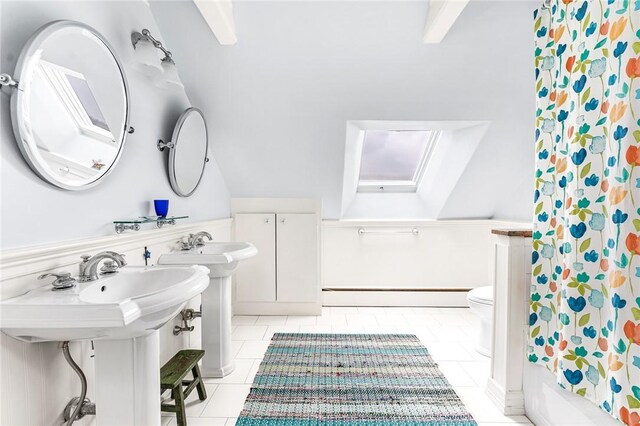 full bath featuring a baseboard radiator, vaulted ceiling with skylight, toilet, tile patterned floors, and a sink