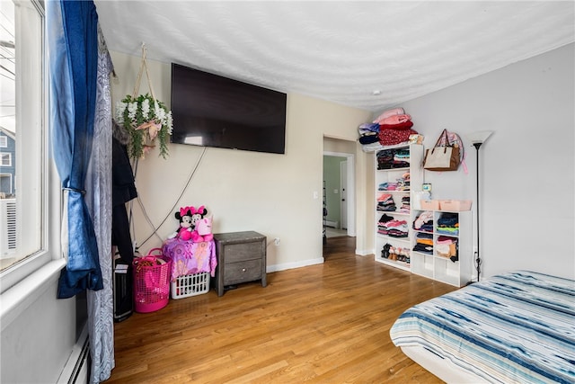 bedroom featuring baseboards, baseboard heating, and wood finished floors