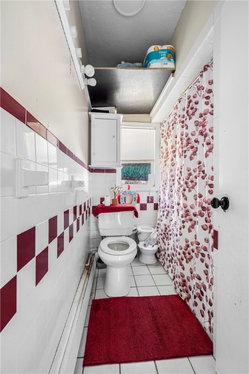 bathroom with tile patterned flooring, tile walls, and toilet