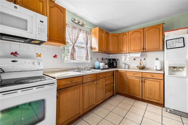 kitchen featuring a sink, white appliances, brown cabinets, and light countertops