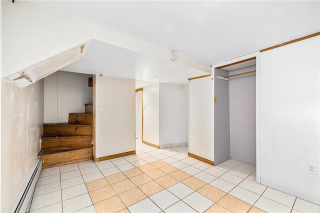 finished below grade area with light tile patterned flooring, baseboard heating, and stairway