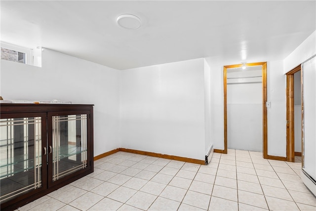 empty room with light tile patterned floors, baseboards, and baseboard heating