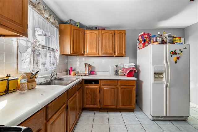 kitchen featuring a sink, brown cabinets, white fridge with ice dispenser, and light countertops