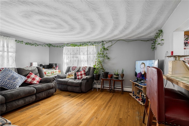 living area featuring a baseboard heating unit, a textured ceiling, and wood finished floors