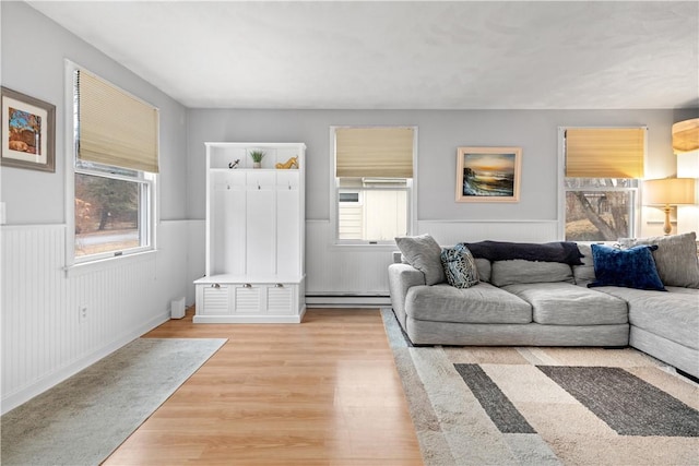 living area featuring baseboard heating, wainscoting, and wood finished floors