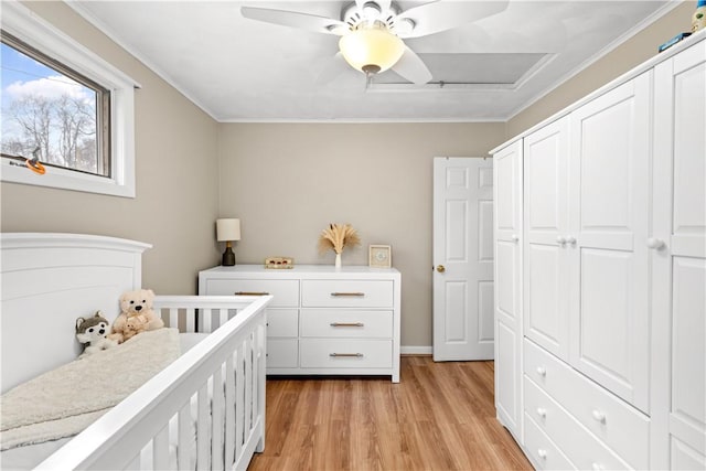 bedroom featuring crown molding, ceiling fan, baseboards, light wood-style floors, and a closet