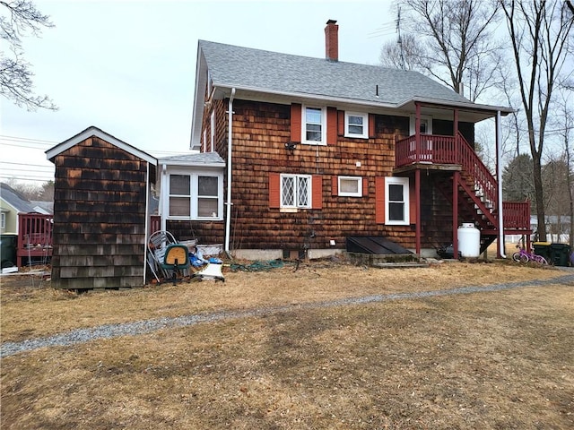 rear view of property with a chimney and a shingled roof