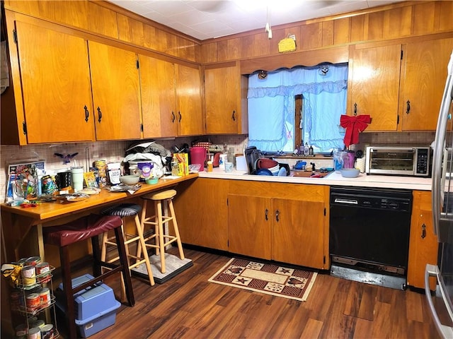 kitchen with a toaster, dishwasher, light countertops, brown cabinets, and dark wood-style flooring