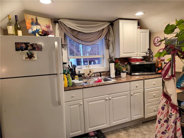 kitchen with stainless steel microwave, recessed lighting, freestanding refrigerator, white cabinetry, and a sink