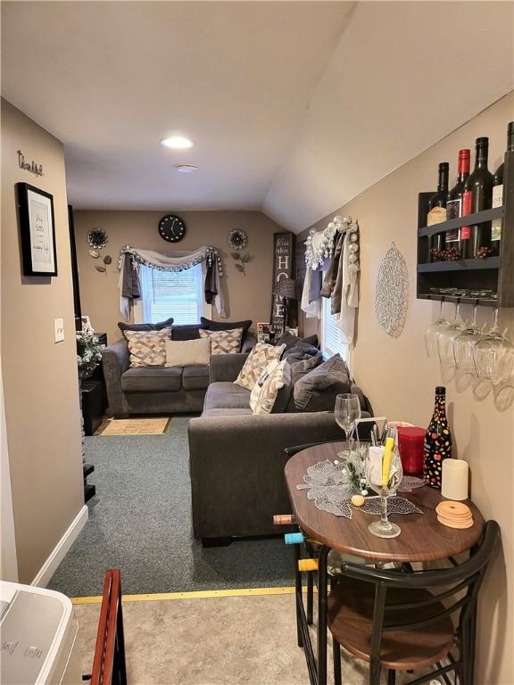 carpeted living room with baseboards and vaulted ceiling