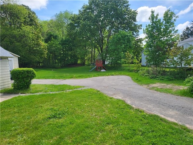 exterior space featuring driveway, a playground, and a yard