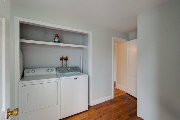 washroom featuring laundry area, wood finished floors, separate washer and dryer, and baseboards