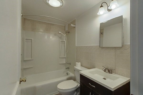 bathroom with toilet, tub / shower combination, tile walls, and vanity