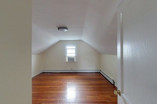 bonus room featuring baseboard heating, wood finished floors, and vaulted ceiling