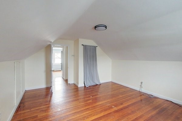 additional living space with lofted ceiling, wood finished floors, and baseboards