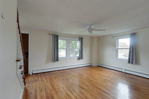 unfurnished room featuring baseboard heating, ceiling fan, and light wood finished floors