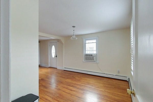 interior space with cooling unit, baseboards, baseboard heating, and wood finished floors