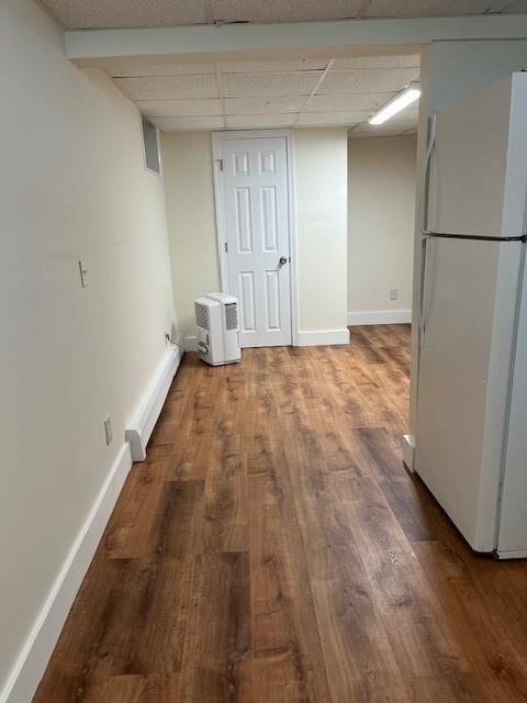 interior space featuring a paneled ceiling, baseboards, wood finished floors, and freestanding refrigerator