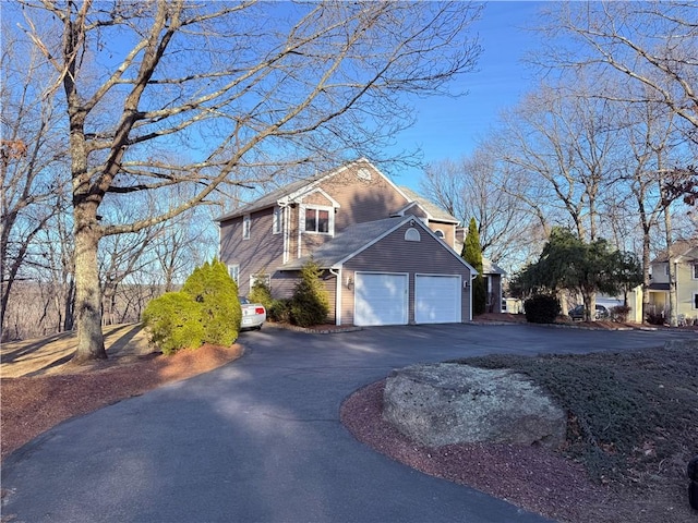 view of side of property with aphalt driveway and an attached garage