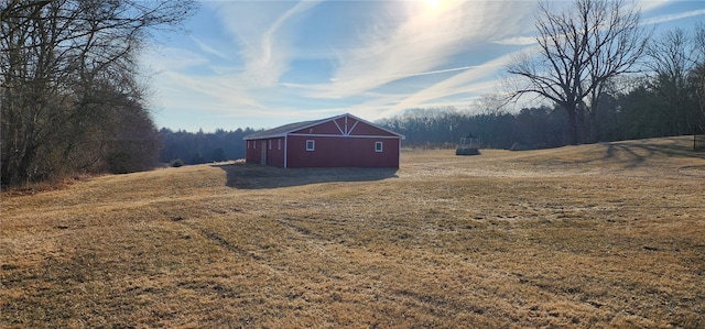 view of yard with an outbuilding, a view of trees, and a barn