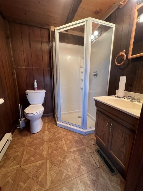 bathroom with wood walls, a stall shower, and a baseboard heating unit