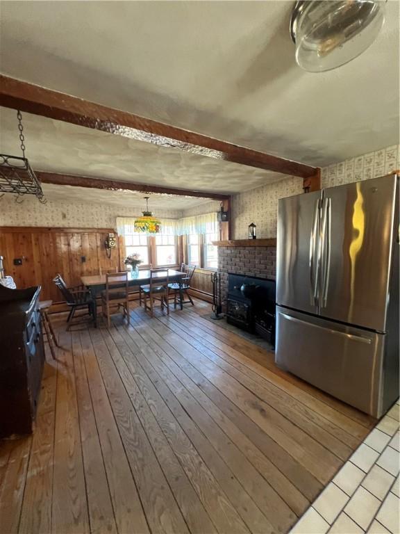 interior space with a brick fireplace, beamed ceiling, and wood-type flooring