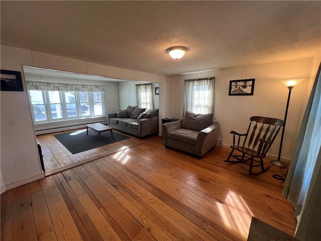 living area featuring a baseboard radiator, baseboards, and wood-type flooring