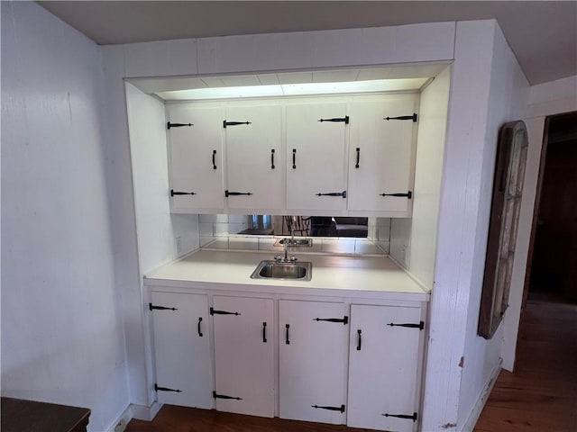 kitchen with white cabinetry, decorative backsplash, light countertops, and a sink