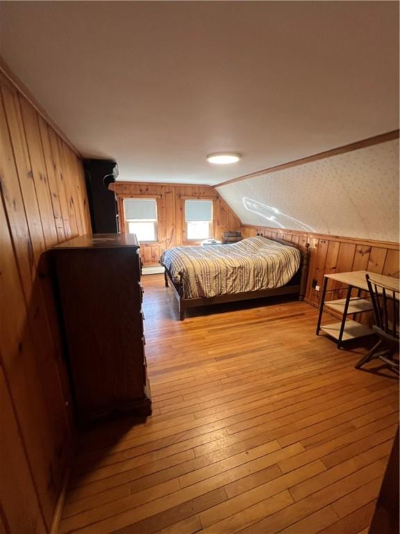 bedroom with wood walls, lofted ceiling, and hardwood / wood-style floors