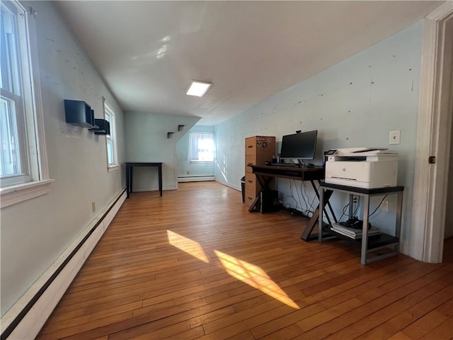 home office featuring baseboard heating, vaulted ceiling, and hardwood / wood-style flooring