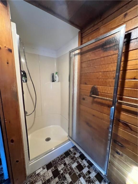 bathroom featuring tile patterned floors, a stall shower, and wood walls