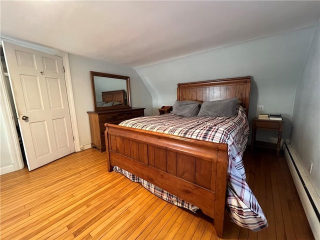 bedroom with baseboard heating, baseboards, and light wood-style floors