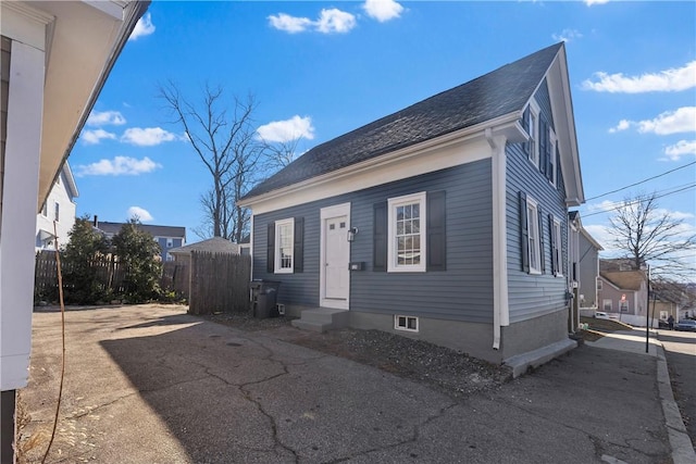 view of front of property featuring entry steps, fence, and a shingled roof