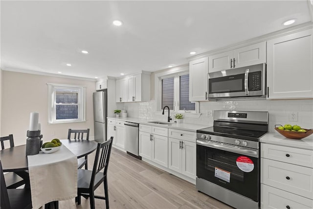 kitchen featuring a sink, light countertops, white cabinets, appliances with stainless steel finishes, and light wood-type flooring