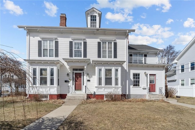 italianate house featuring a balcony, fence, and a chimney