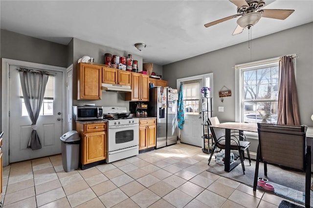 kitchen featuring light tile patterned floors, ceiling fan, under cabinet range hood, appliances with stainless steel finishes, and dark countertops