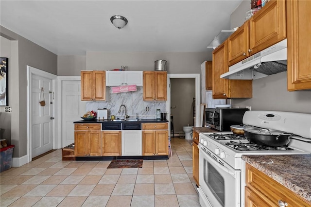 kitchen featuring dark countertops, stainless steel microwave, gas range gas stove, under cabinet range hood, and a sink